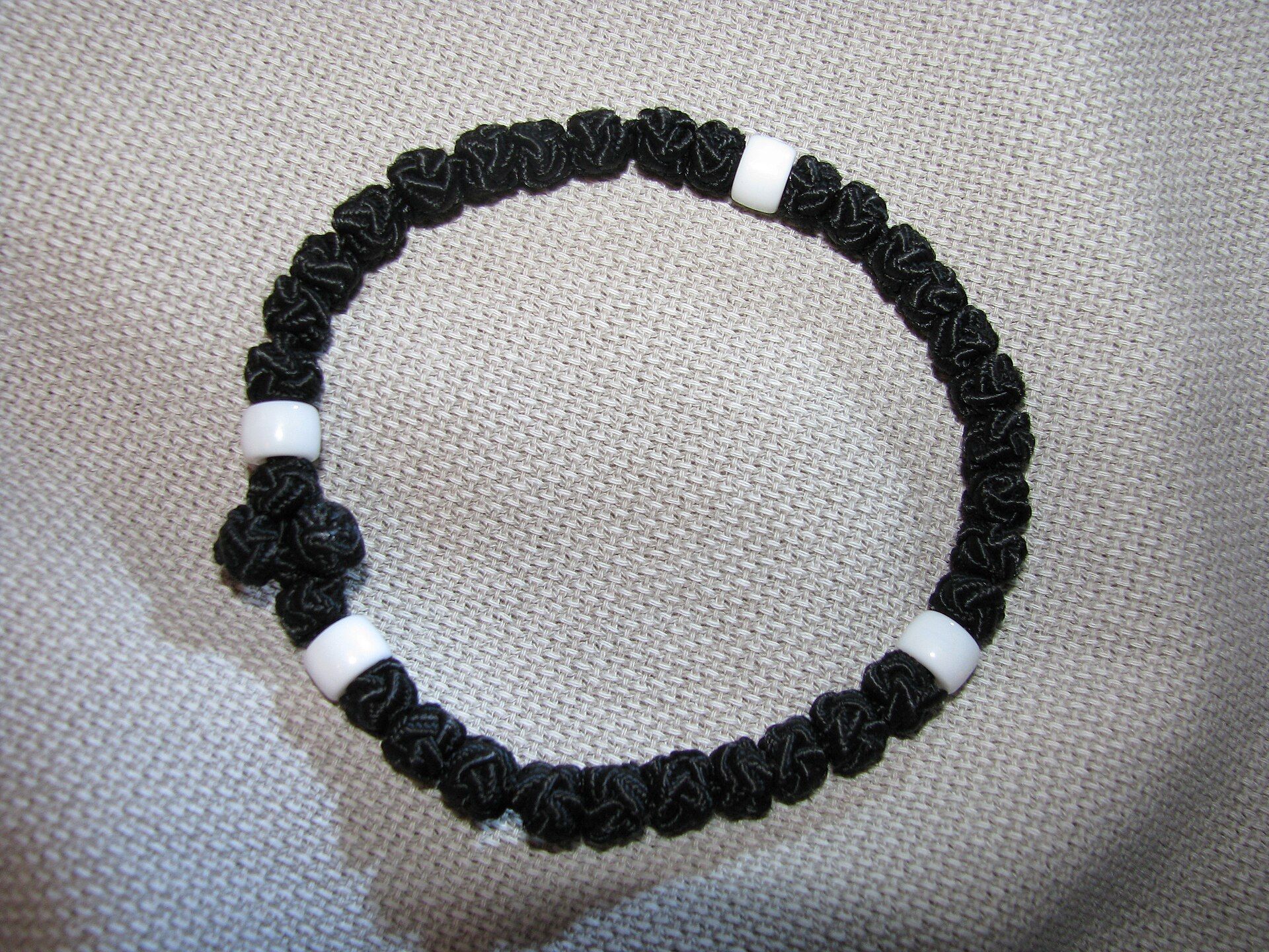 A black knotted Orthodox prayer bracelet resting on woven cloth